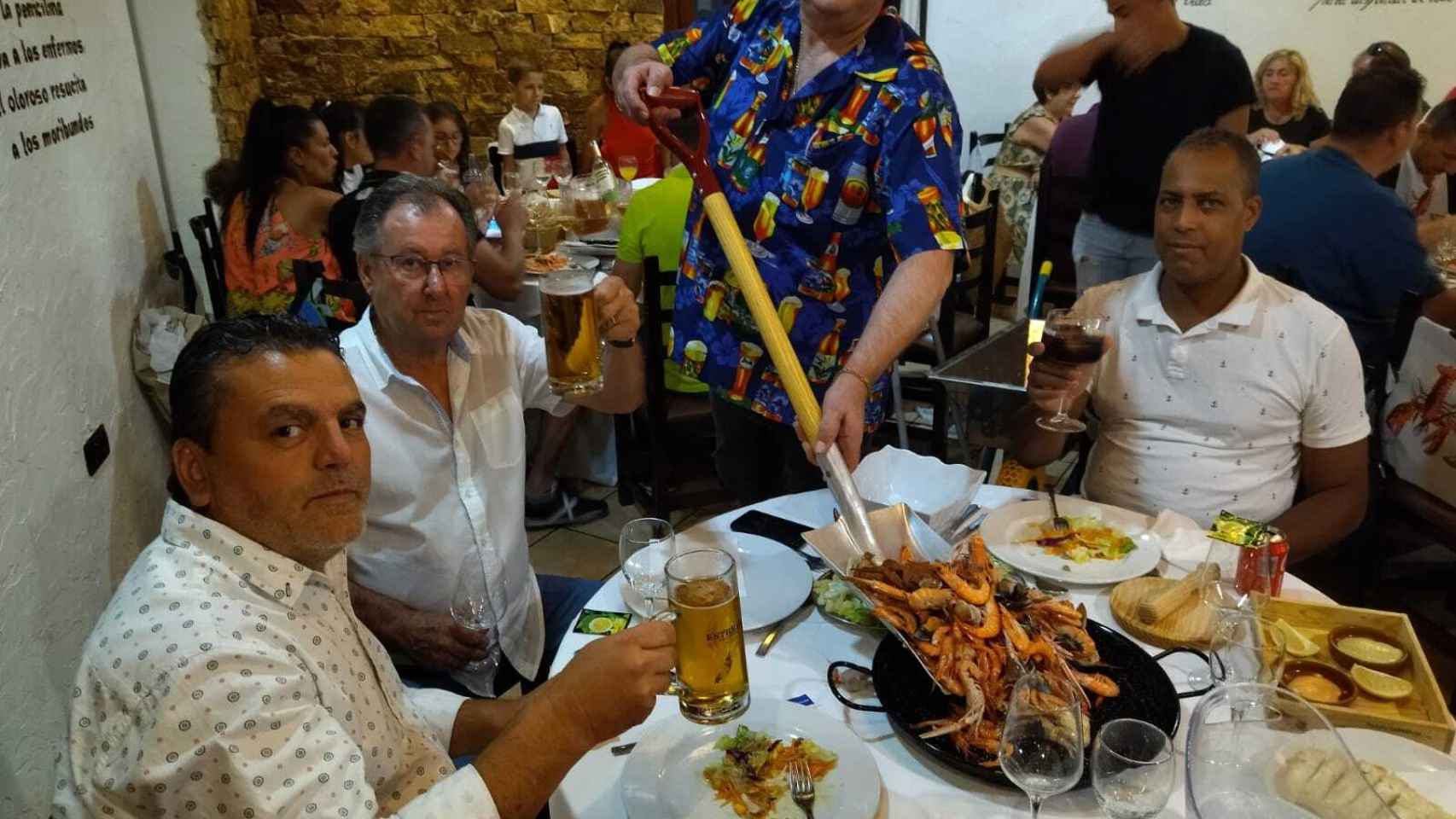Pedro sirve con una pala el marisco en su restaurante.