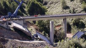 Operarios y grúas trabajan durante el desmontaje del tercer y último vano del viaducto de la A6 en Vega de Valcarce (León).