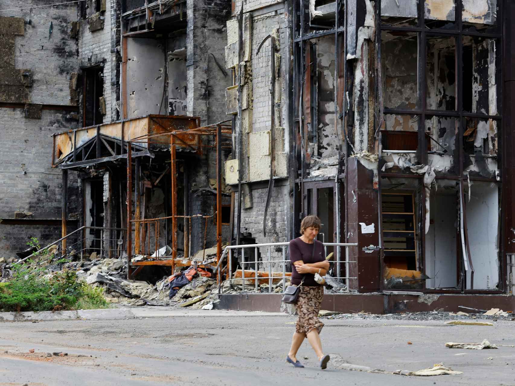 Una mujer pasea rodeada de destrucción en Mariúpol, Ucrania.