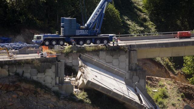 Operarios y grúas trabajan durante el desmontaje del tercer y último vano del viaducto de la A6.