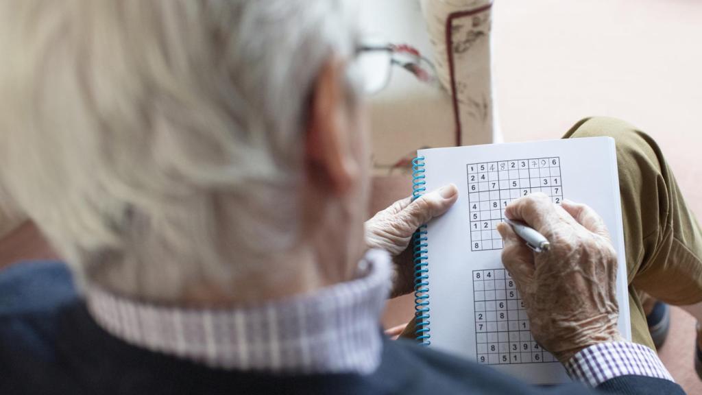 Una persona mayor resuelve un sudoku.