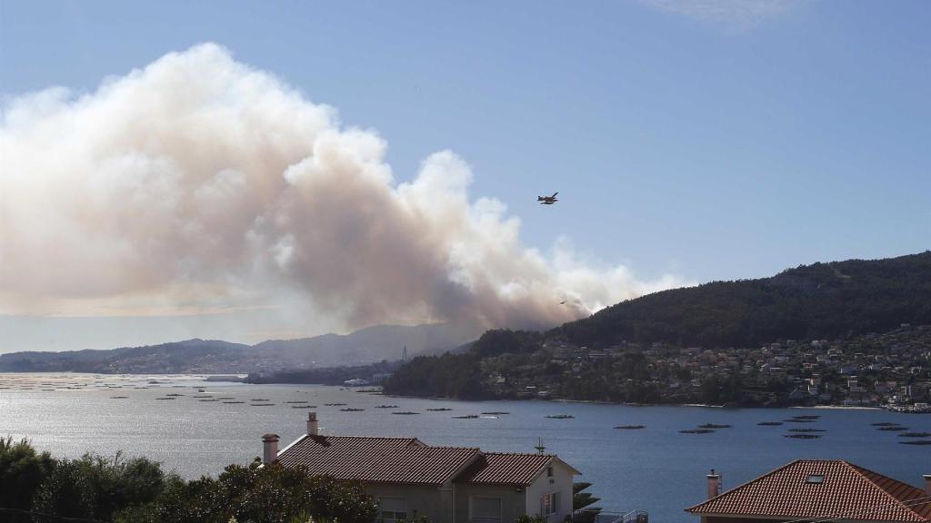 Un helicóptero al lado de una columna de humo en el incendio de Moaña (Pontevedra).