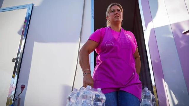 Una mujer cargando las botellas de agua para su negocio.