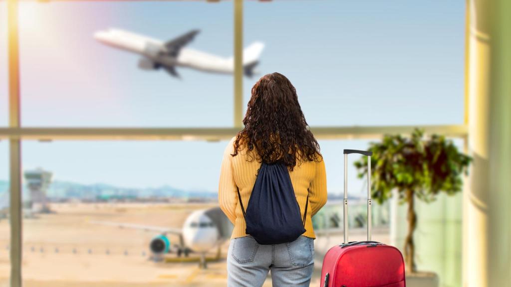 Mujer viendo despegar un avión en el aeropuerto.