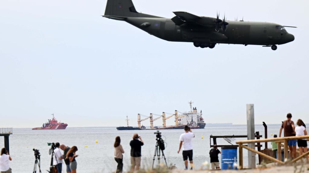 El buque frente a la Playa de Levante, en la Línea, mientras aterriza un avión militar de Gibraltar.