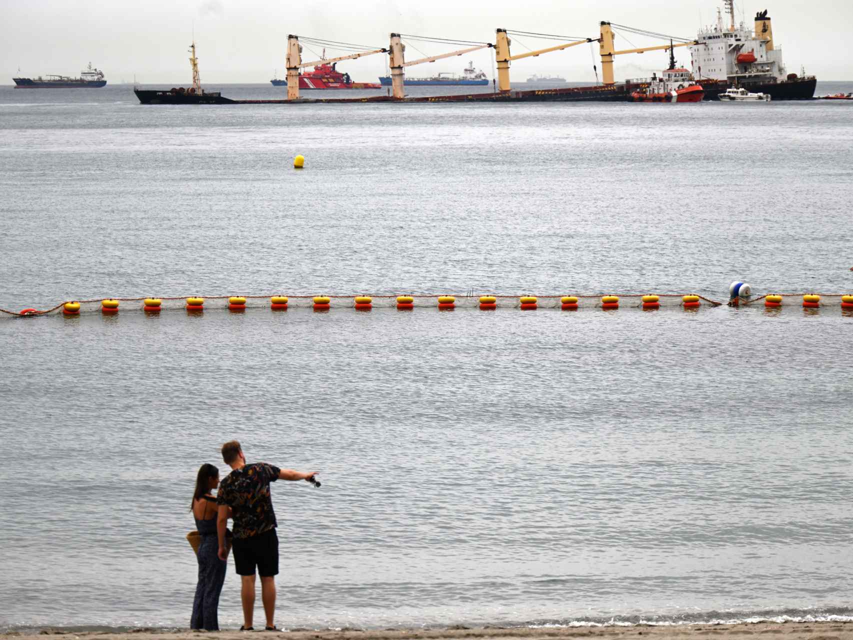Una pareja observa el buque siniestrado desde Catalan Bay, en la Playa de La Caleta.
