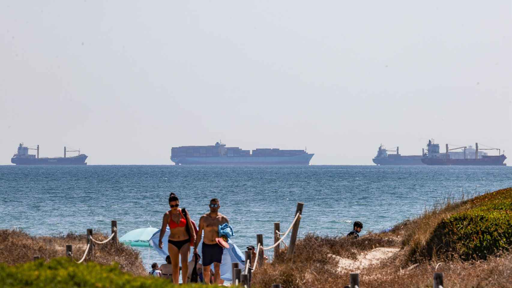 Varios turistas en una playa de Valencia, con cruceros al fondo, este mes de agosto.