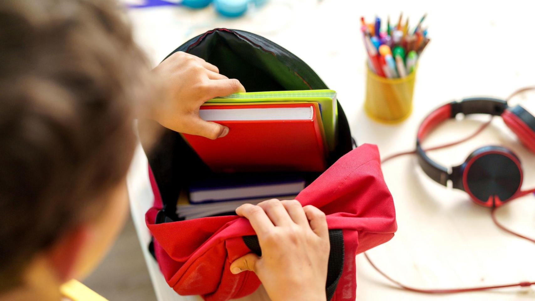 Un joven con su material escolar en clase