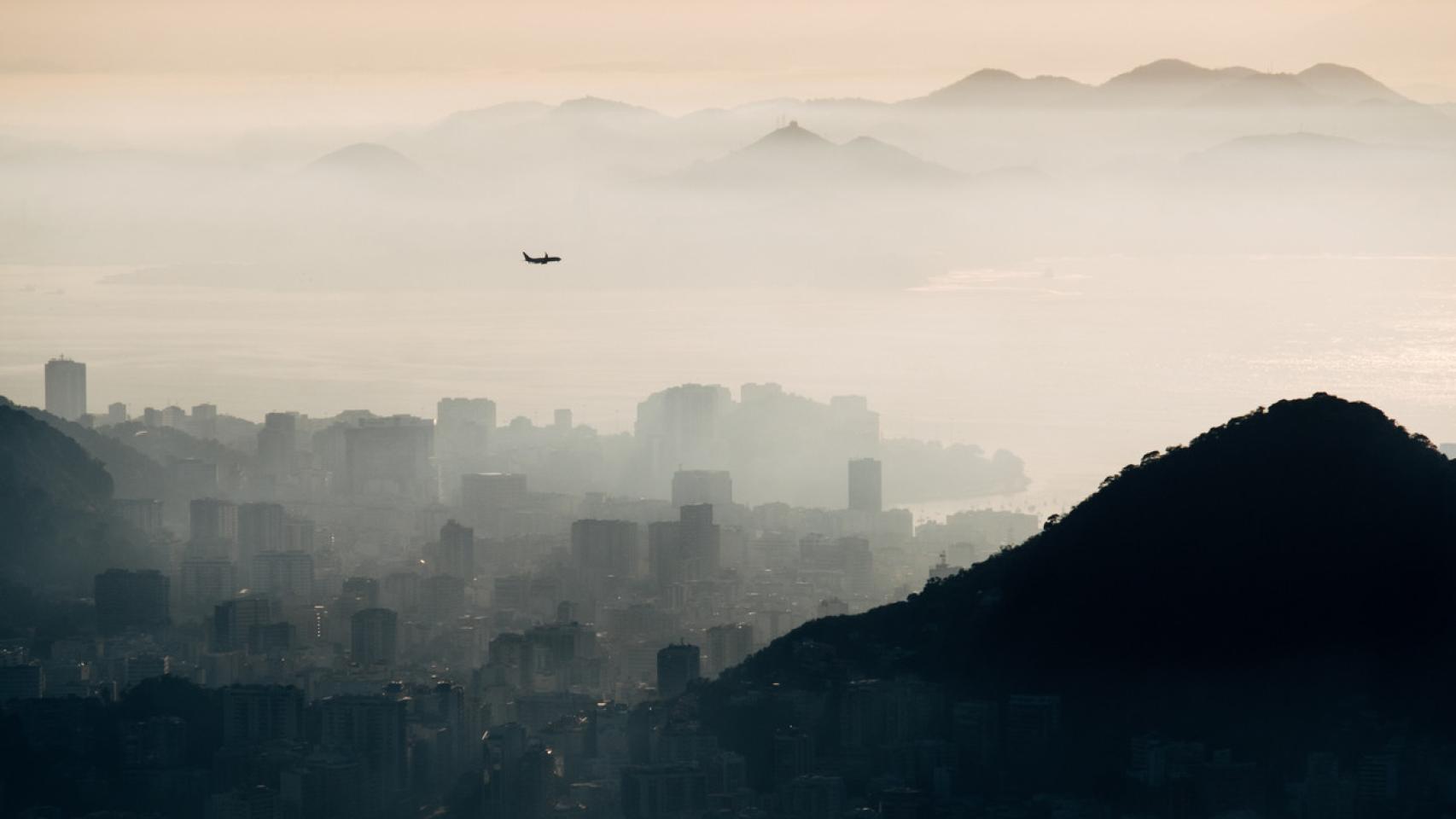 Un avión sobrevuela una ciudad cubierta de contaminación