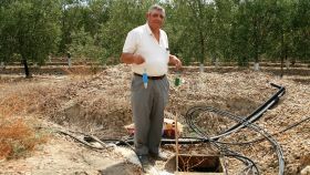 El zahorí o buscador tradicional de agua subterránea Miguel Fernández posa con sus péndulos en el pozo que halló y con el que riega sus olivos, en Fuentes de Andalucía (Sevilla).