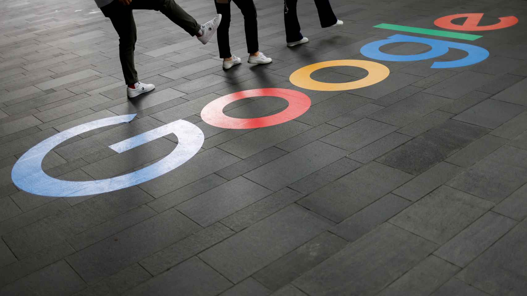 Varias personas junto al logo de Google en el exterior de las oficinas de la compañía en Singapur.