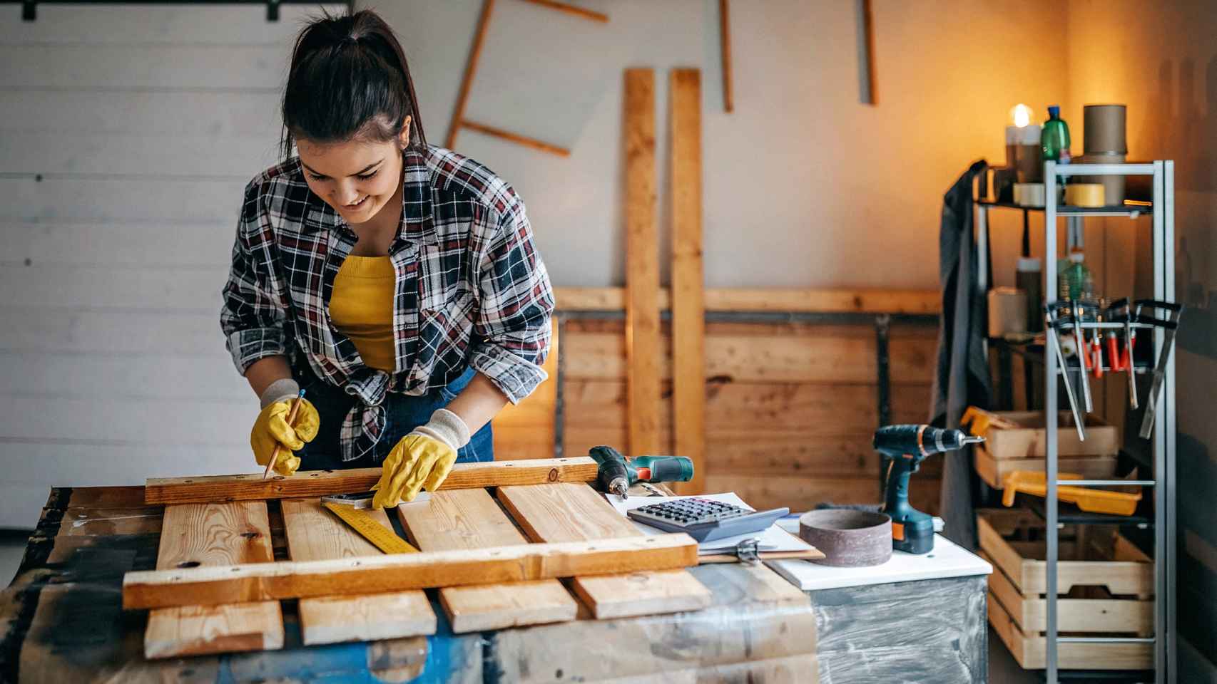 Una mujer en casa fabricando un objeto con tablones de madera.