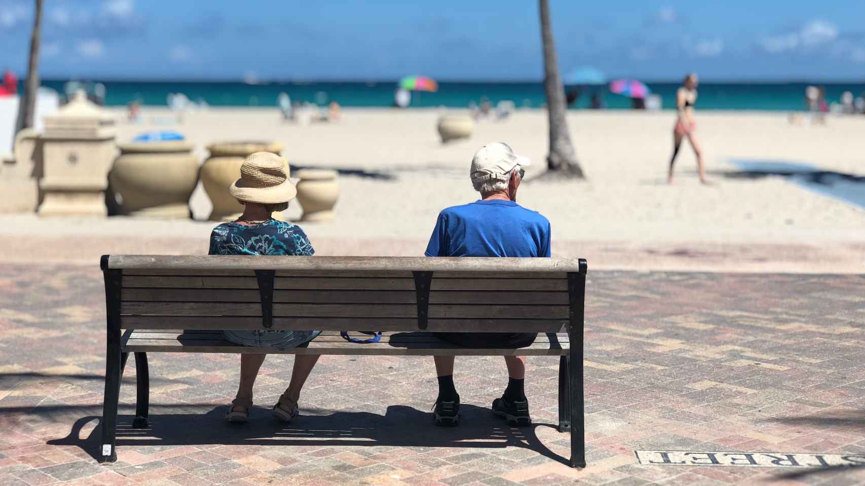 Dos jubilados sentados en un paseo marítimo.