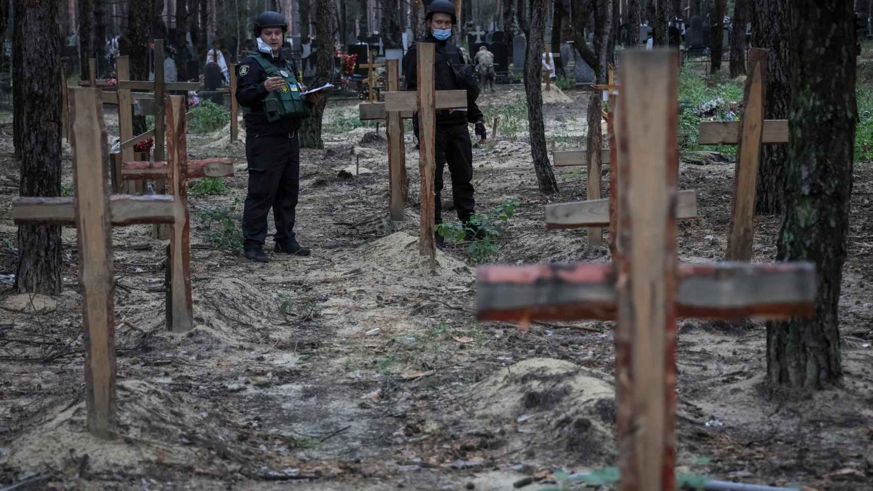 La policía trabaja en un lugar de entierro masivo durante una exhumación, mientras continúa el ataque de Rusia a Ucrania, en la ciudad de Izium