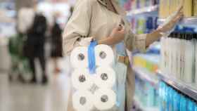 Una mujer compra un paquete de rollos de papel higiénico.