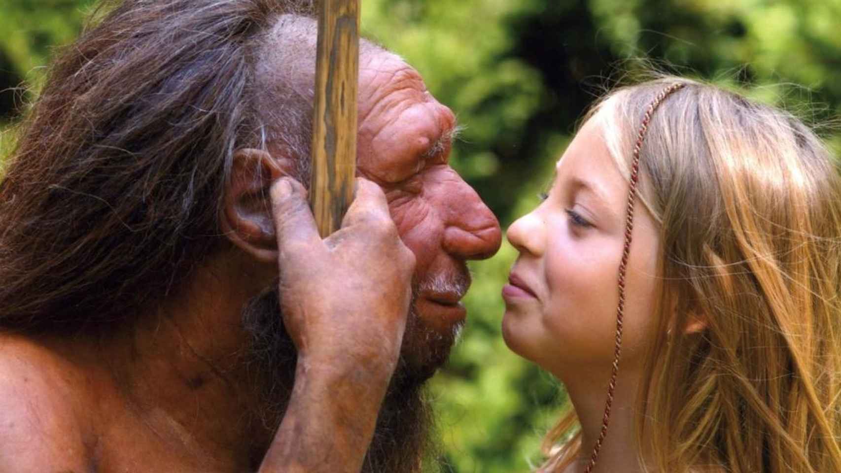 Una niña posa junto a la reproducción de un neandertal.