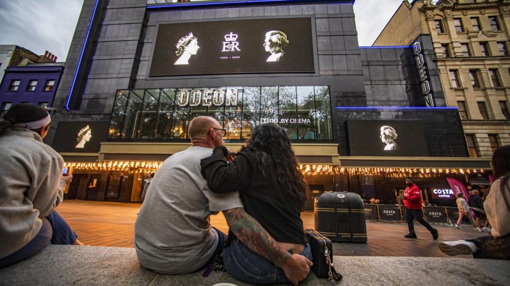 Imagen de una pareja esperando ver en las pantallas el funeral de Isabel II.