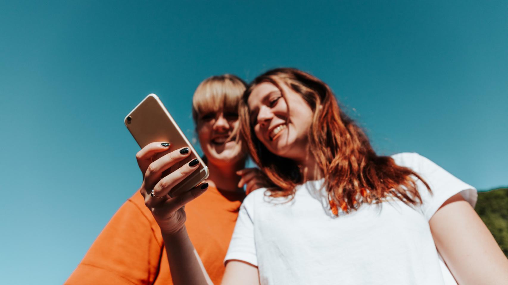 Imagen de archivo de chicas mirando un teléfono móvil