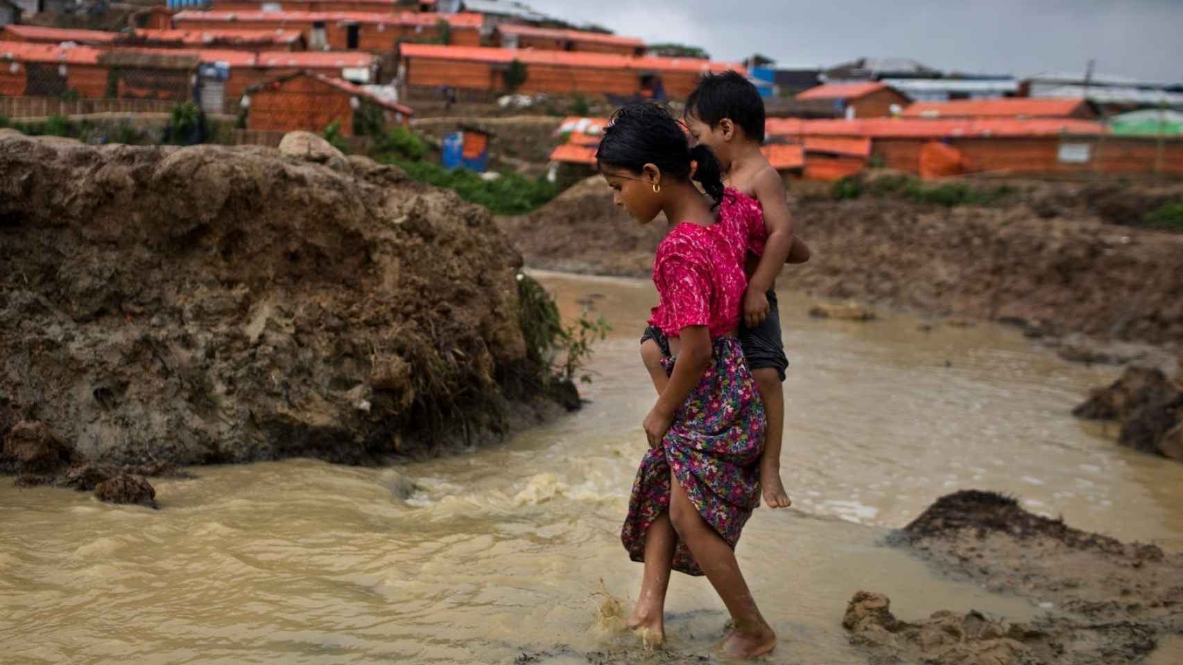 Una niña roghingya lleva a su hermano en un asentamiento de refugiados en Cox Bazar
