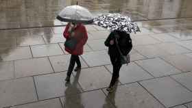 Imagen de archivo de dos personas andando un día de lluvia