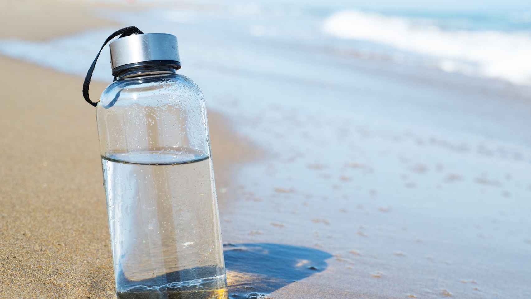 Botella de agua reutilizable en la playa