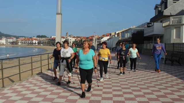 Vecinos de Nigrán practicando Marcha Nórdica por el paseo de la playa de Panxón.