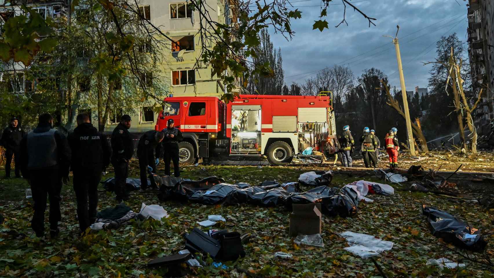 Bomberos ucranianos atienden a los heridos tras el bombardeo en Zaporiyia con varios muertos sobre el suelo.