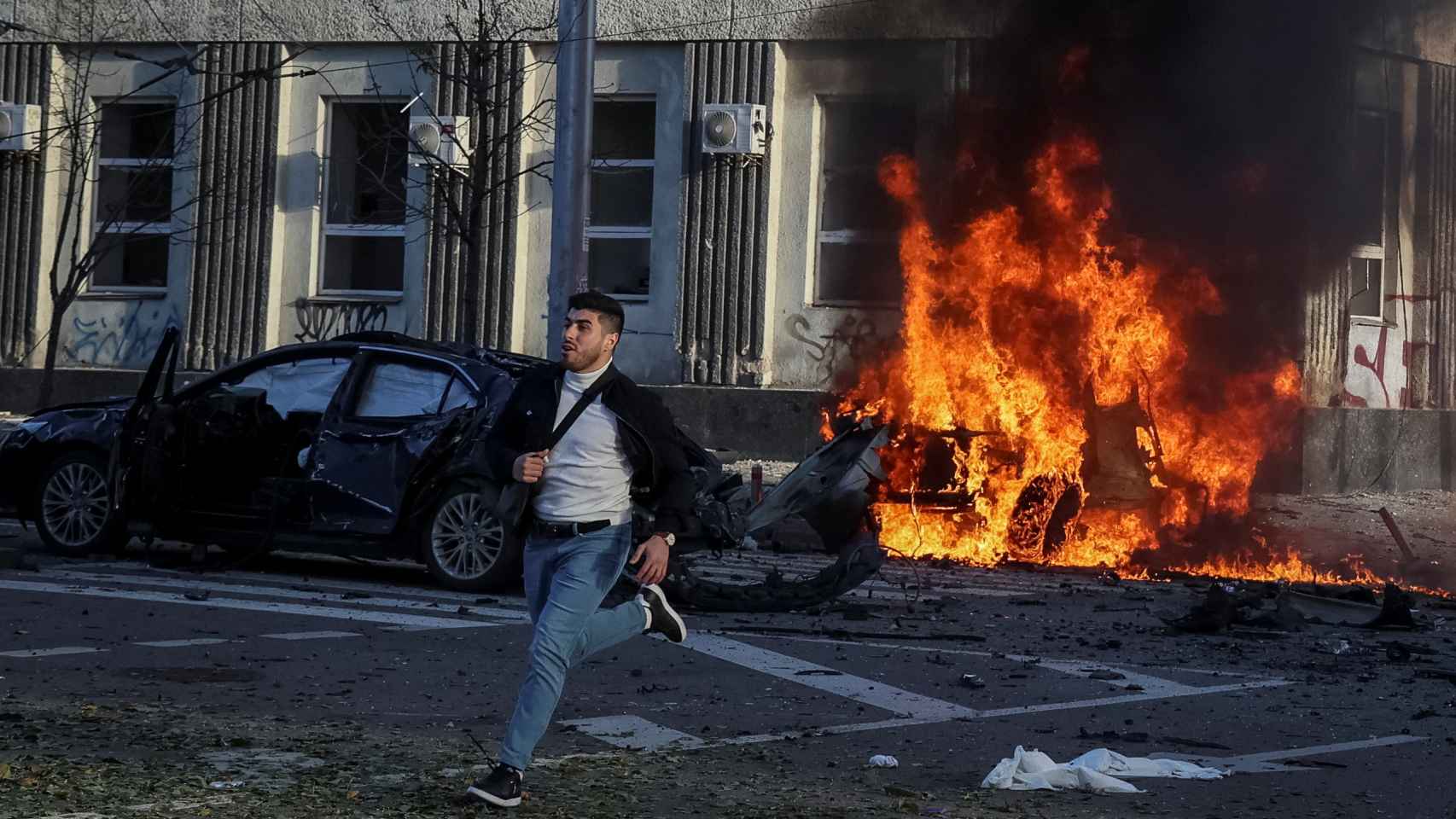 Un joven huye de los coches en llamas en del centro de Kiev tras el ataque ruso de este lunes.