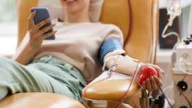 Una chica mira el móvil mientras dona sangre