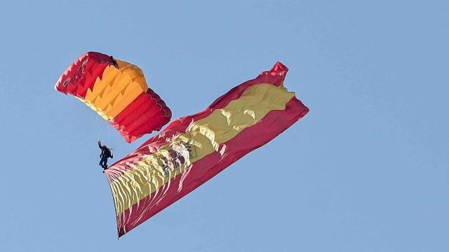 Imagen de un paracaidista desplegando la bandera de España en un desfile del 12 de octubre