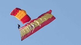 Un paracaidista porta banderas de España en el desfile militar de las Fuerzas Armadas de 2022.