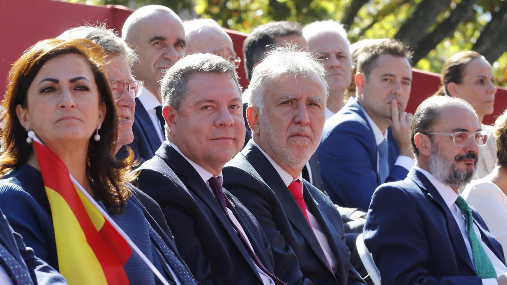 Emiliano García-Page con otras personas en la tribuna de autoridades del desfile de la Fiesta Nacional