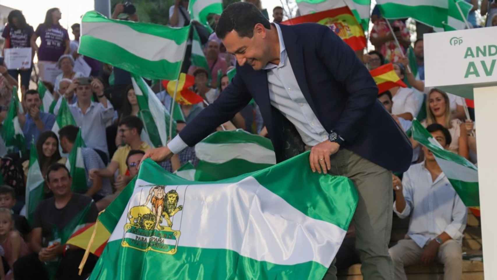 El presidente de la Junta, Juanma Moreno, coge una bandera andaluza durante el primer acto de campaña del pasado 19 de junio.