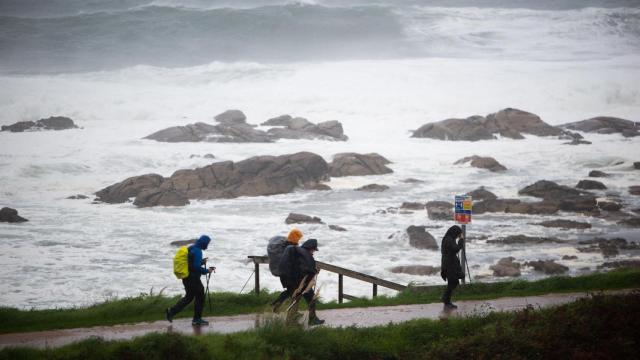 Varios peregrinos realizan el Camino de Santiago a pesar del temporal en la zona de Santa Maria de Oia.