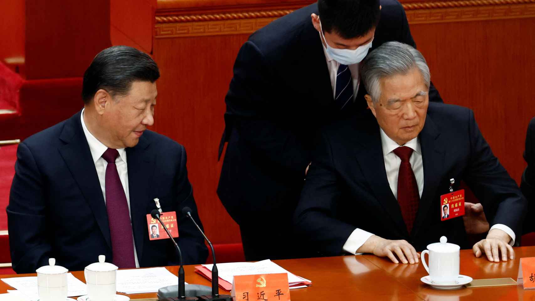 Xi Jinping (izquierda) y Hu Jintao (derecha) levantado por su asistente en la clausura del XX Congreso del PCCh.