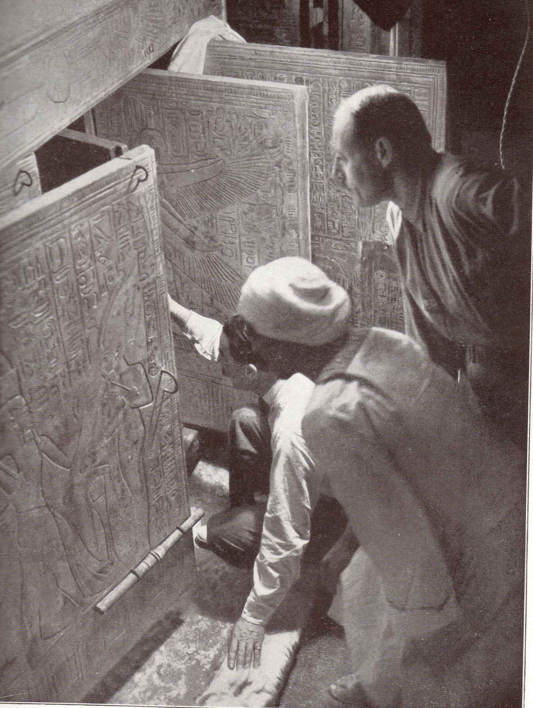 Howard Carter, arrodillado, abriendo una de las puertas de las capillas que protegían al faraón niño.
