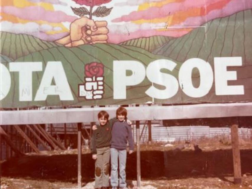 Daniel Sánchez Arévalo con su hermano, delante del cartel de su padre, el día que el PSOE gana las elecciones.