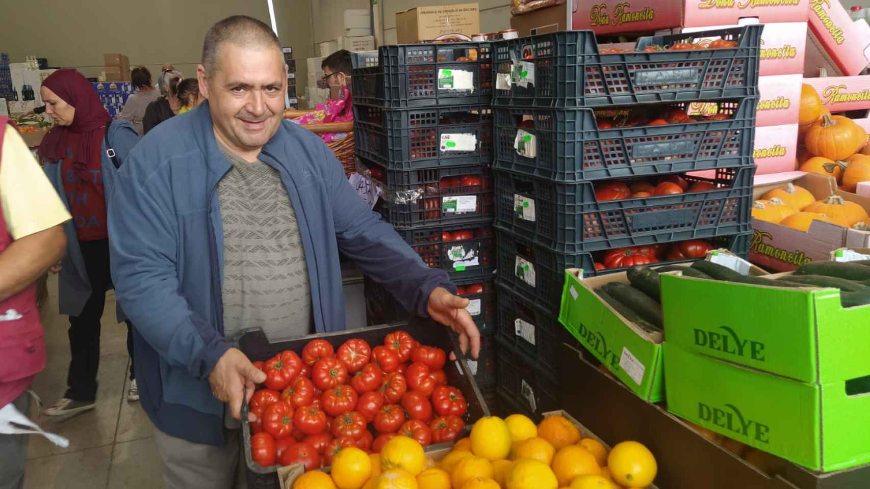 Carlos Moreno muestra los tomates que está vendiendo. De fondo, más cajas con los mismos.