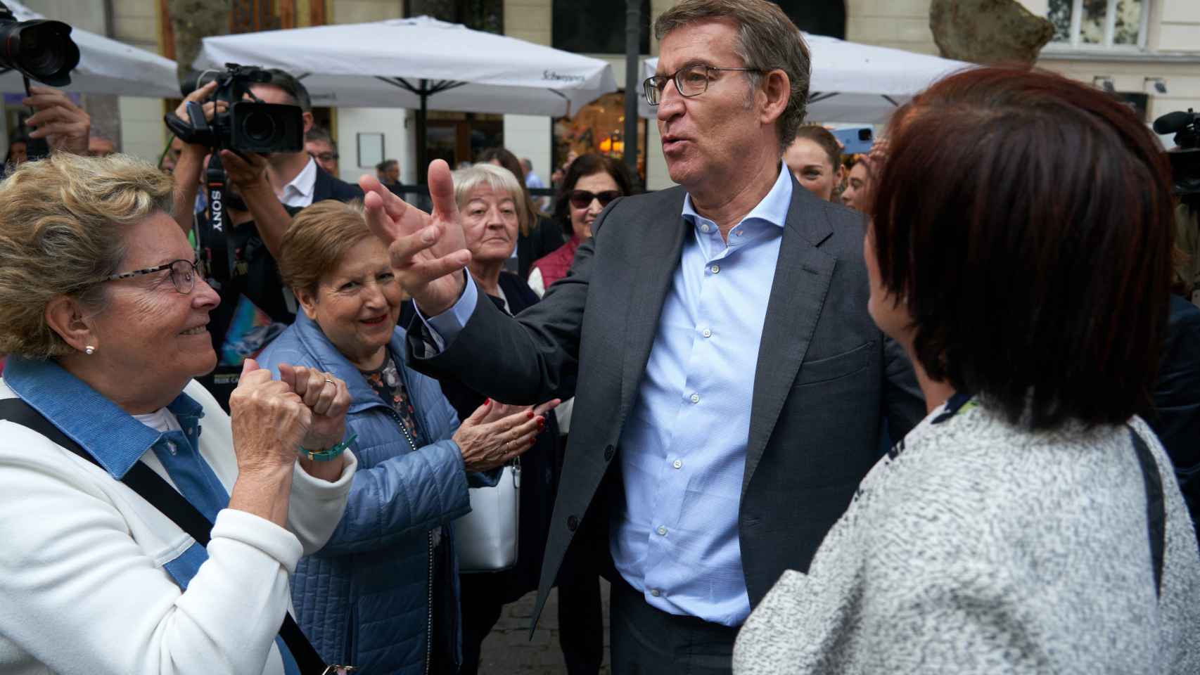 El presidente del PP, Alberto Núñez Feijóo, saluda a varias vecinas durante un paseo por el centro de Vitoria, este viernes.