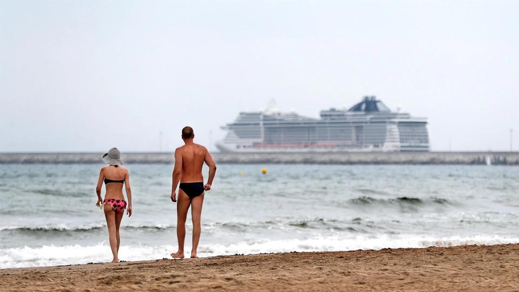 Dos bañistas en un día nublado observan un crucero, en imagen de archivo.