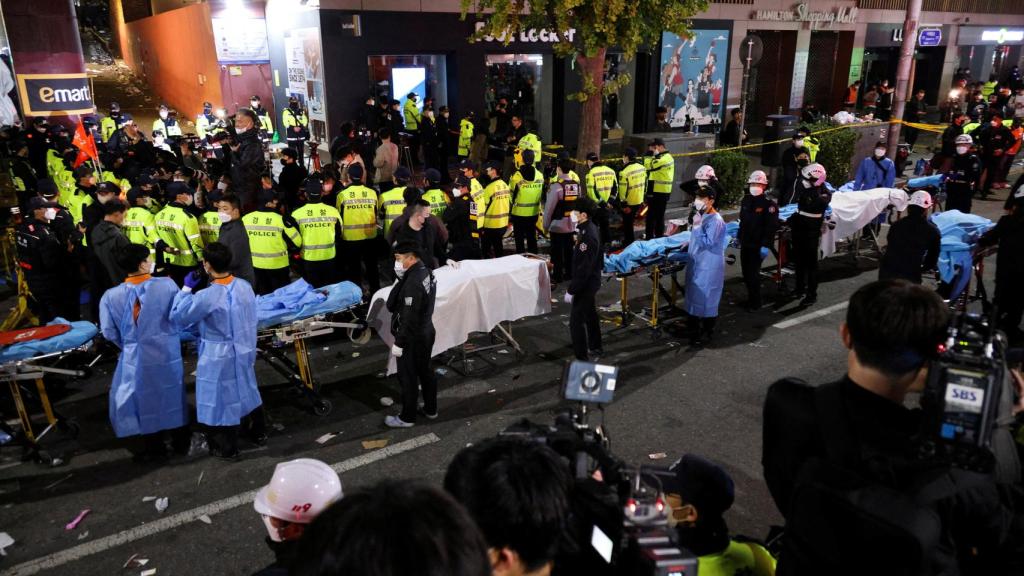 Una fila de camillas y de sanitarios atienden a los heridos en una calle de Seúl tras la tragedia de este sábado.