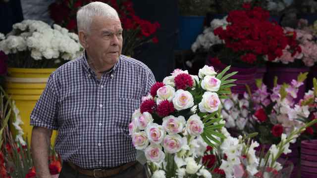 Un hombre compra flores para recordar a un ser querido en el Día de Todos los Santos.