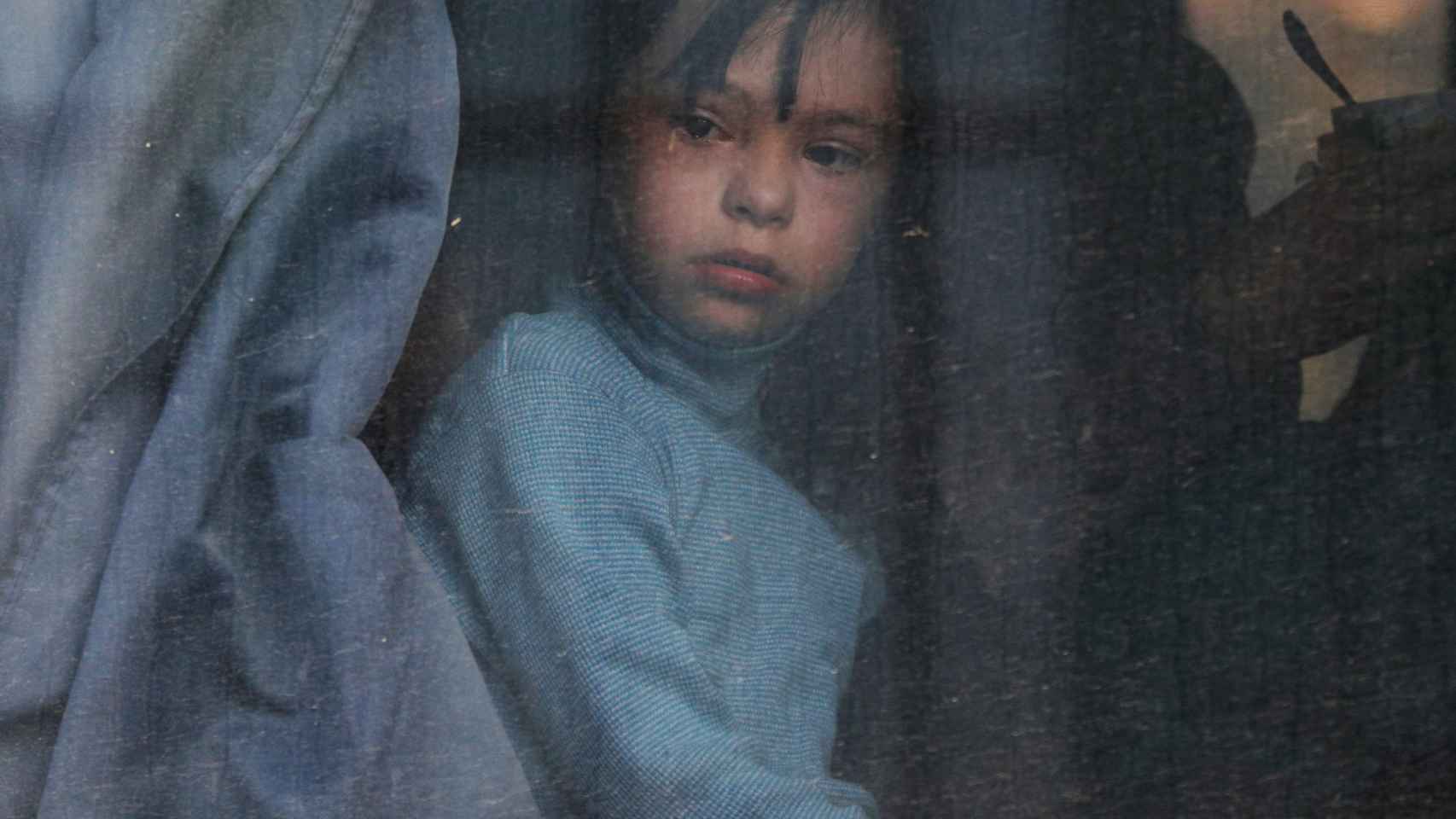 Un niño mira por la ventana de un autobús de deportados de Jersón.