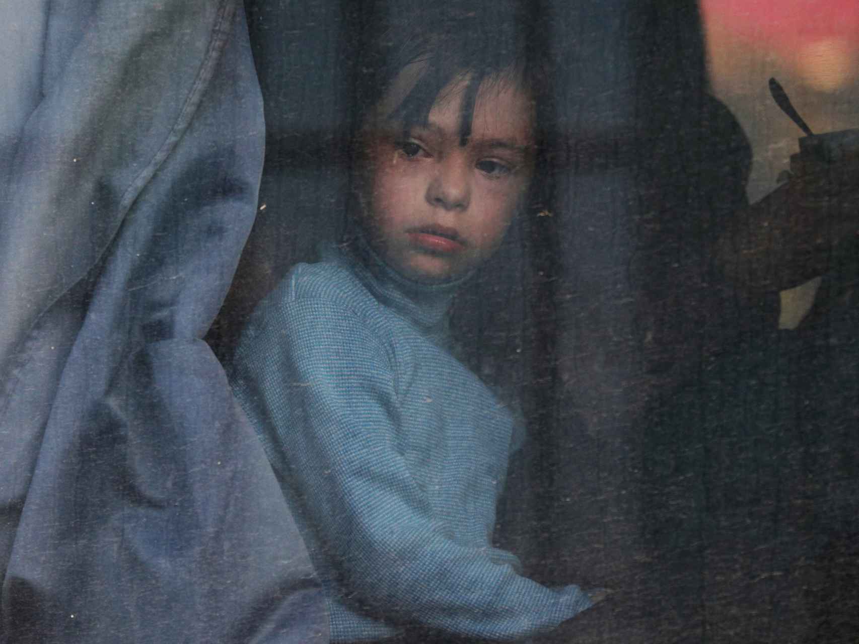Una niña mira por la ventana de un autobús de deportados de Jersón.