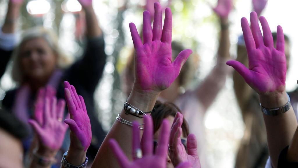 Manos de hombres y mujeres pintadas de rosa por el Día Mundial de la Lucha contra el Cáncer de Mama.