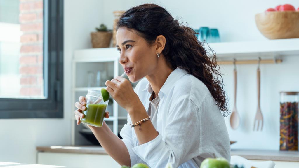 Una mujer tomando un zumo verde.