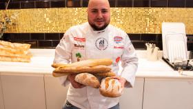 El maestro panadero Julio López, sujetando cinco panes.