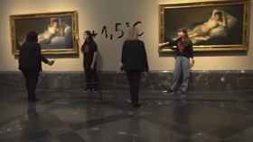 Dos vigilantes de sala se aproximan a los activistas que se pegaron a los marcos de las dos 'Majas' de Goya este sábado en el Museo del Prado. Foto: EFE/Futuro Vegetal