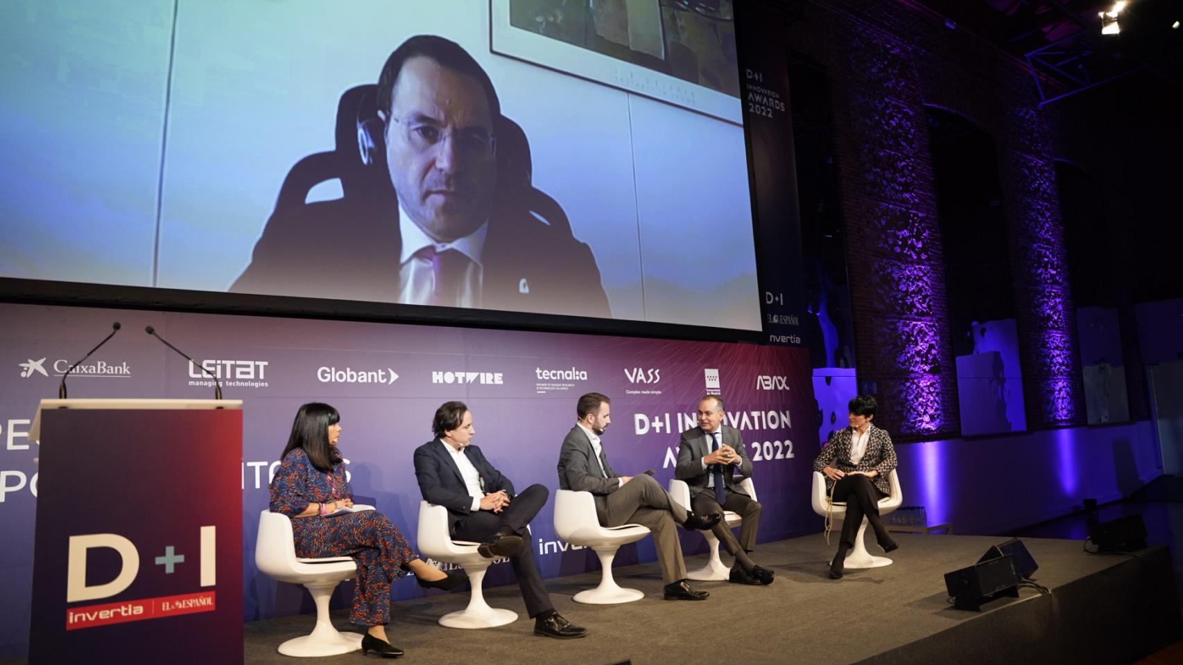 De izquierda a derecha en el estrado: Ludi García, directora de Hotwire España; Luis Ureta, director general de Globant en España; Alberto Iglesias, subdirector de D+I;  Pablo Cortés Achedad, secretario general de Investigación e Innovación de la Junta de Andalucía; y Alaitz Landaluze, coordinadora general de Políticas de Innovación de la Agencia Vasca de Innovación (Innobasque). En la pantalla:  Daniel Alvear, director general de Industria, Energía y Minas de Cantabria.