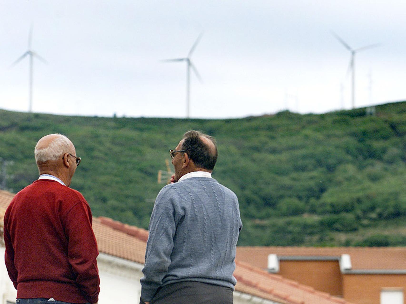 Dos vecinos observan un antiguo parque eólico en Barruelo de Santullán (Palencia)